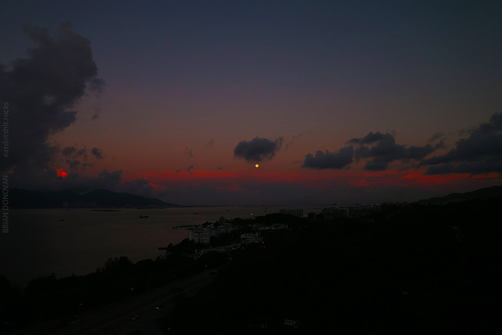 The Moon is hovering just above a layer of clouds.