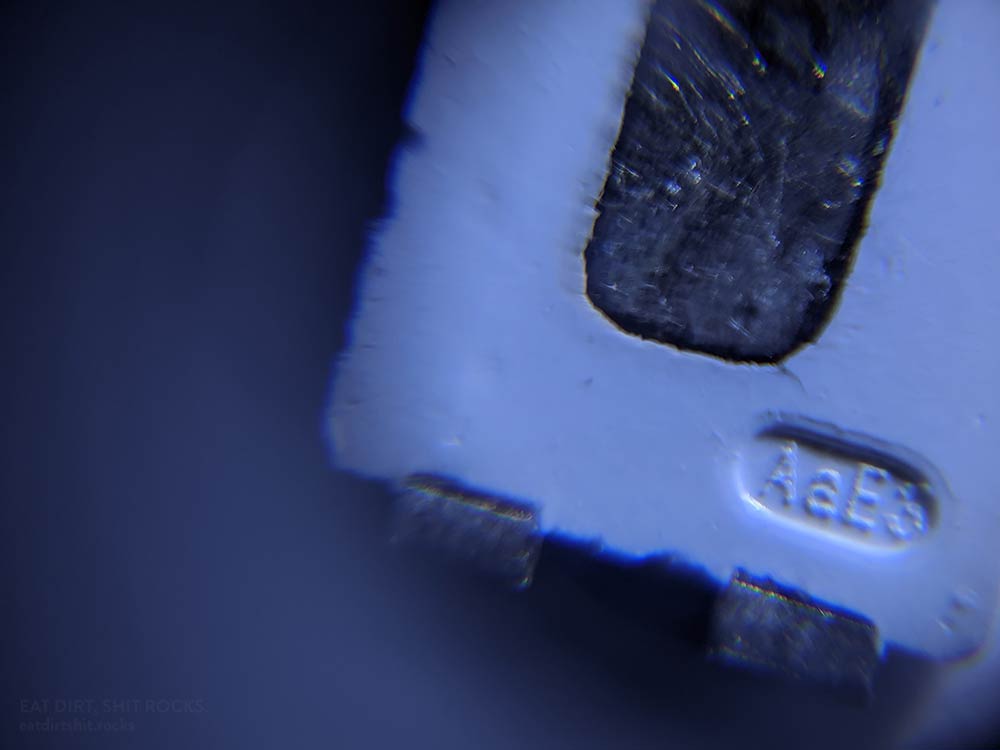 A closeup of the negative end of the underside of the same LED shown in the preceding image. Text reads 'AaE3'.